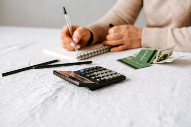 Person reviewing debt consolidation and debt settlement paperwork with a calculator and monthly bills on the floor